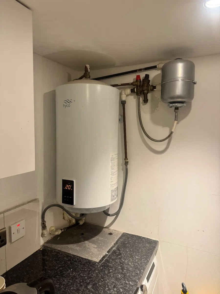 A small unvented cylinder with its expansion vessel and valve group fitted on a kitchen wall