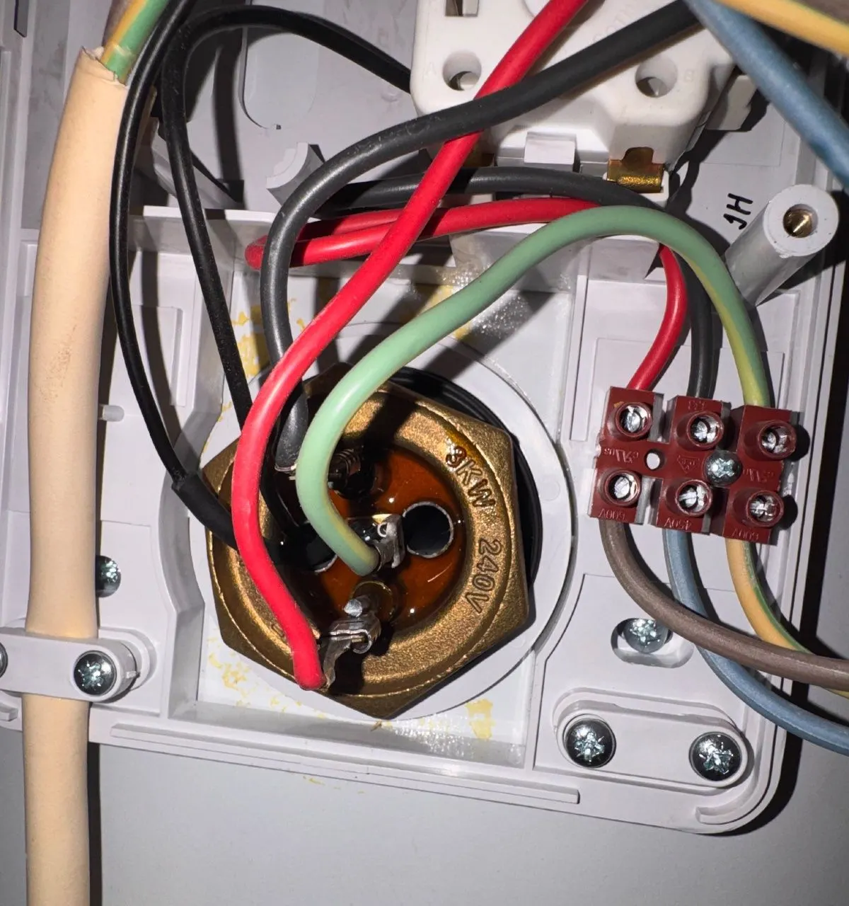 Close-up of an immersion heater element flange with its wiring connected, stamped 3kW 240V, inside the cylinder terminal cover